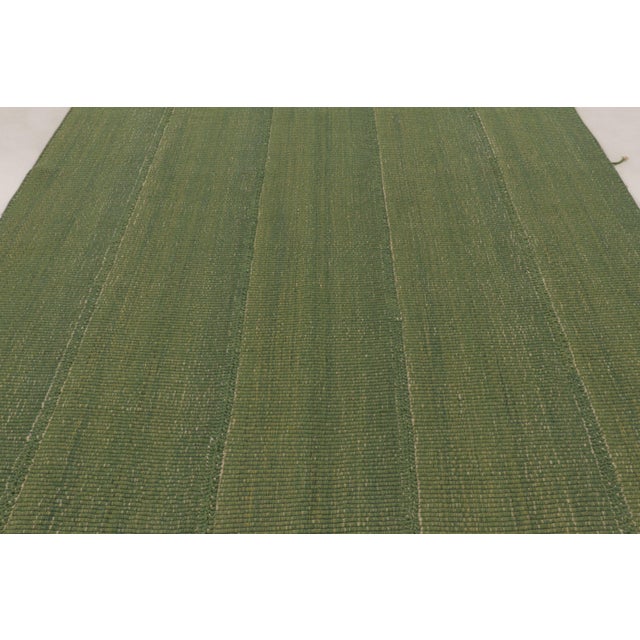 Handwoven in wool, this 8x10 Rez Kilim features layered green tones accented by subtle linear striping. Its textured...