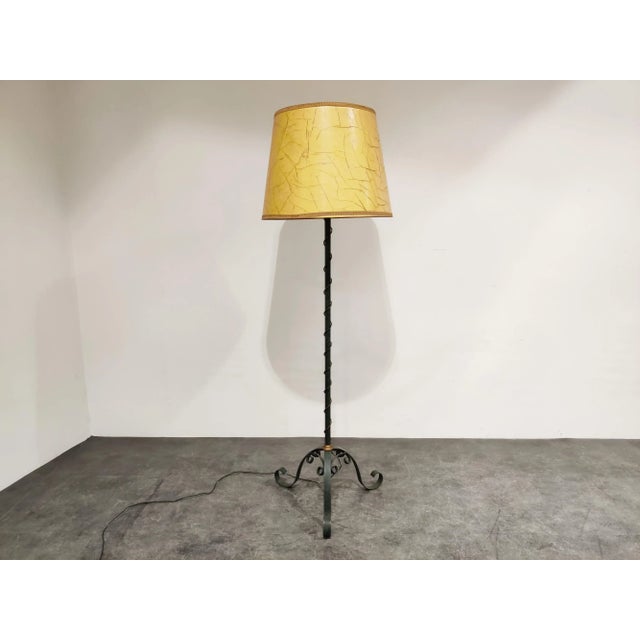 Elegant midcentury wrought iron floor lamp. Beautiful tripod scroll legs. The floor lamp has it's original parchment lamp...