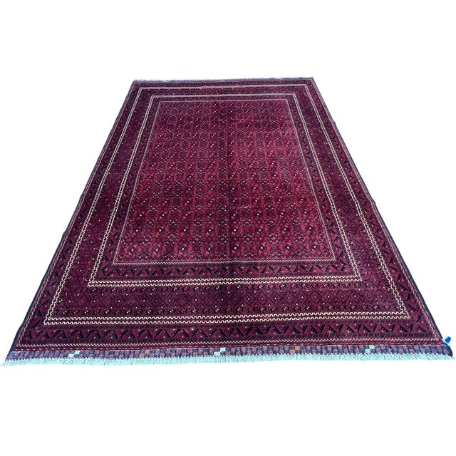 Afghan Turkmen rug, hand knotted in Afghanistan from 100% wool. Measuring 8’3” x 11’, this rug features a rich burgundy...