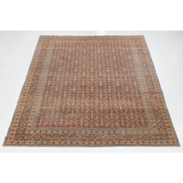Beautiful antique Tabriz hand-knotted wool rug with a red field. This piece features a designed frame with beige and blue...