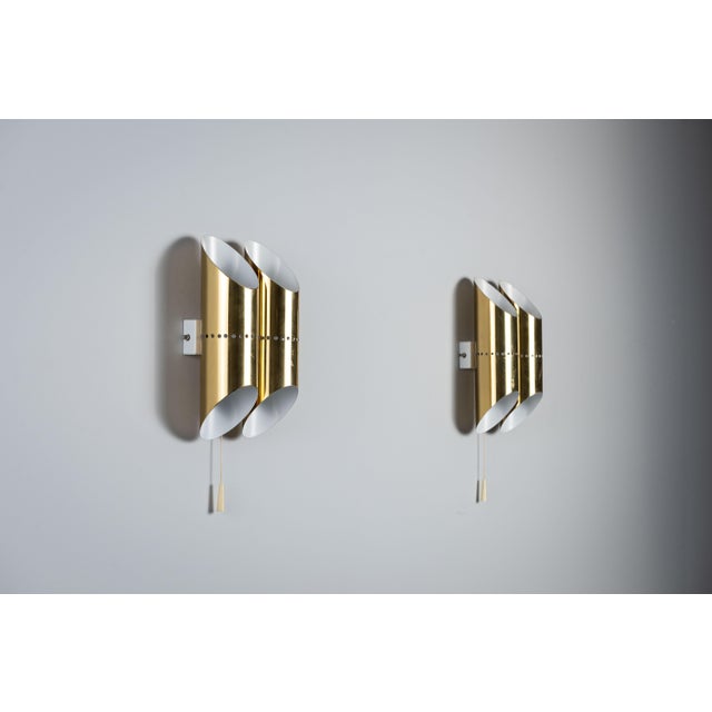 This pair of vintage wall lamps features an elegant brass design with a distinctive double-cylindrical shade. Each...