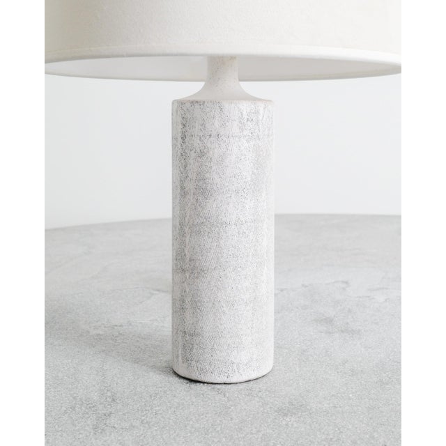 A very rare and iconic French mid century stoneware cylinder table lamp in a white glaze with a decorative pattern...