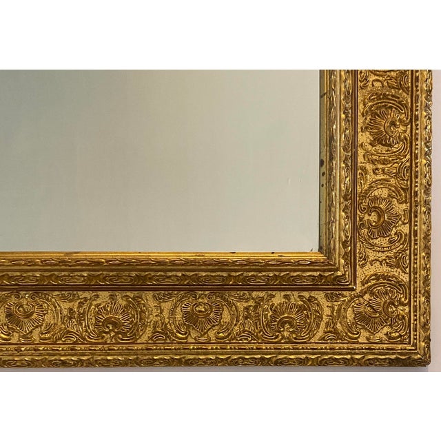 A richly ornamented antique giltwood and gesso wall mirror featuring an elegant Renaissance Revival inspired design with...