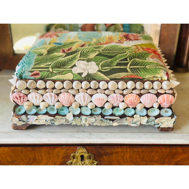 An antique shell-encrusted footstool, beautifully restored with a newly upholstered velvet seat featuring a lush tropical...