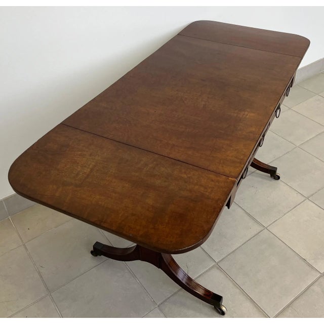 Antique early 19th century Georgian sofa table in the Egyptian Revival manner. Highly figured mahogany with ebonized...