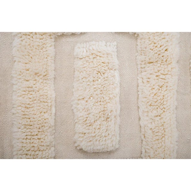 Textured hand-knotted wool rug in Coconut Milk, featuring a structured arrangement of raised rectangular forms. Its...