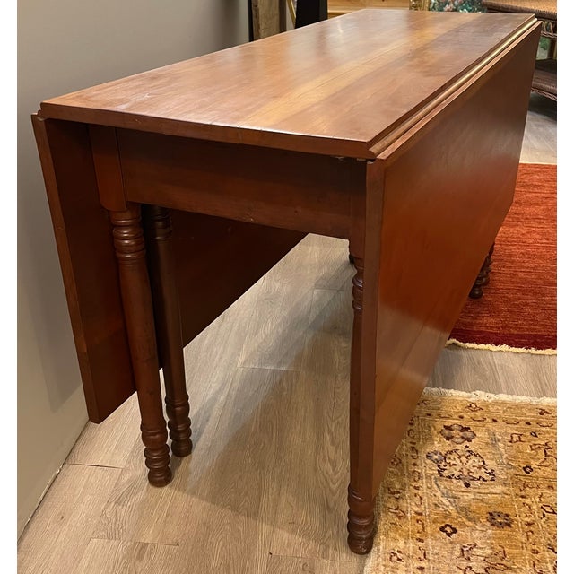 Antique Drop Leaf Cherry Dining Table with Turned Legs. There are a total of 6 legs. Two of the legs swivel to hold up the...