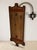 A distinctive vintage wooden coat rack featuring a decorative wooden back panel, multiple curved metal hooks, and a...