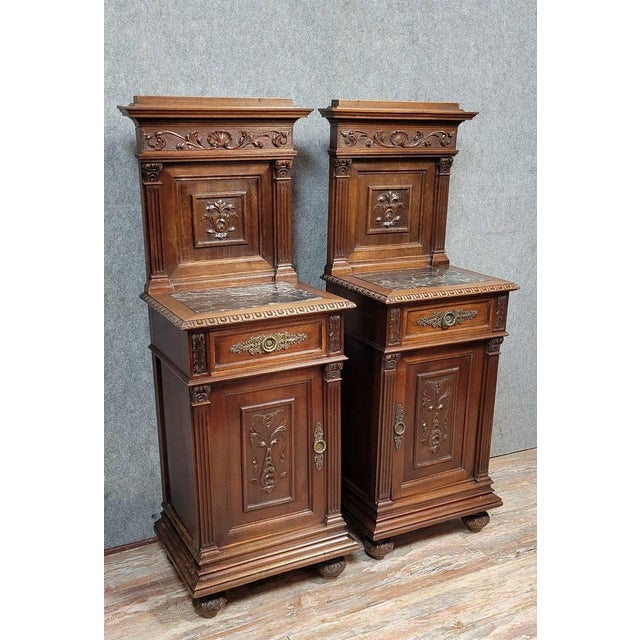 Pair of Renaissance-style bedside tables in carved walnut, 19th century Each opens with one door and one drawer Marble...