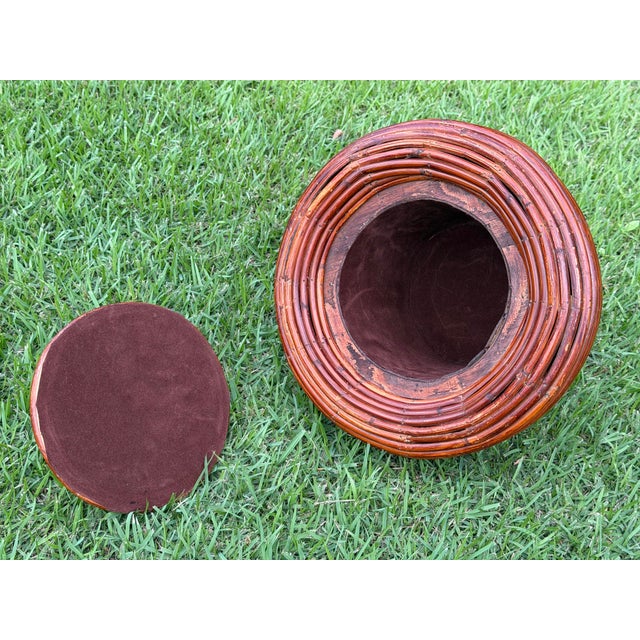Sculptural vintage lidded urn crafted in pencil reed rattan, featuring richly layered horizontal reeds and a warm reddish-...