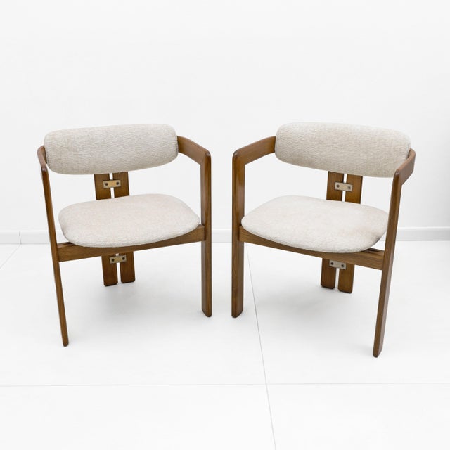 An elegant pair of armchairs. They feature a minimalist, sculptural design defined by a bentwood frame with a warm finish...