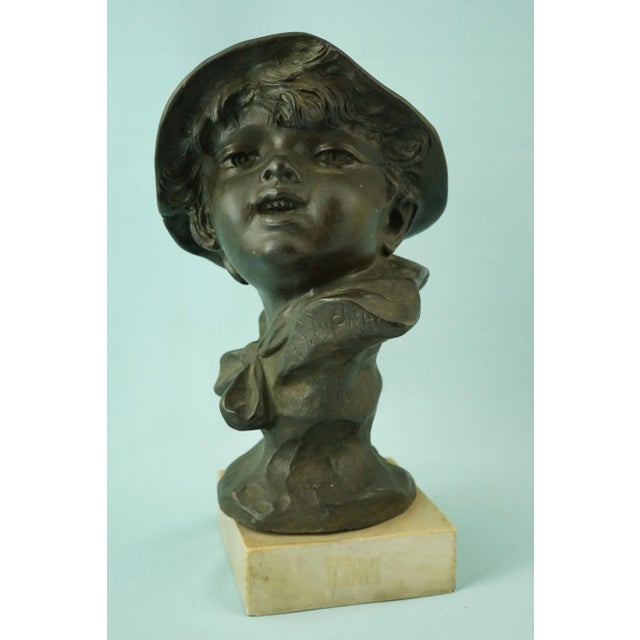 Description of the item: Delightful bronze bust depicting a young boy wearing a hat, mounted on a travertine marble base,...