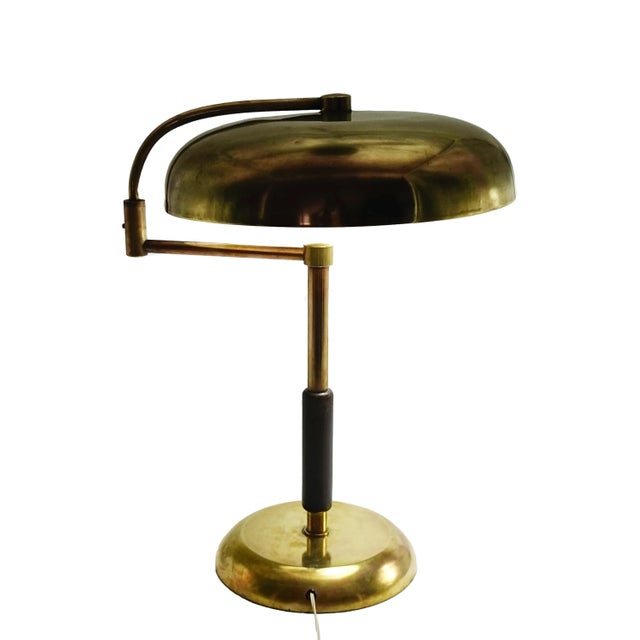Brass desk lamp by Maison Desny featuring elegant, geometric lines and a minimalist design. It has a brass base and stem...