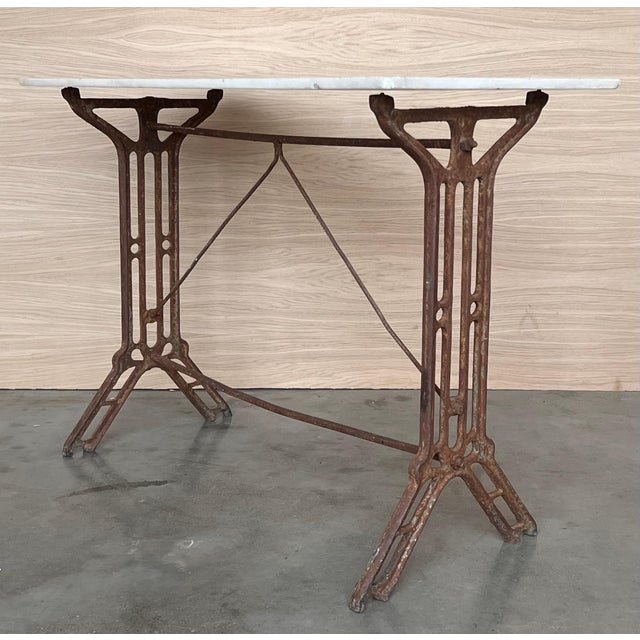 Coffee table with marble top. Item features impressive cast iron construction, two pedestal legs, fancy scroll work to...
