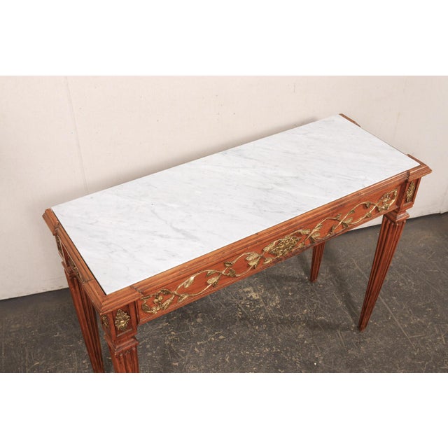 An Italian wood-carved console table, with newer honed marble top, from the early 20th century. This antique table from...