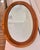 Handsome vintage oval wall mirror featuring a substantial oak wood frame with a warm walnut-stained finish, beautifully...