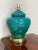 Vintage, glass encased table lamp in a deep teal color set on a brass plinth. The large ginger jar shape on the brass...