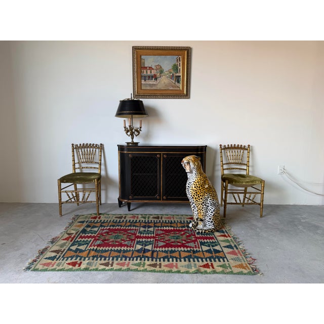 Elegant 1930s Hollywood Regency-style small cabinet featuring a rich ebonized finish accented with giltwood trim. Its...