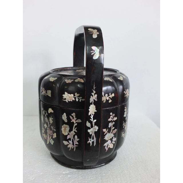 This pretty lacquer basket with an overhead handle has a floral shape and the different lobe show off the individual...