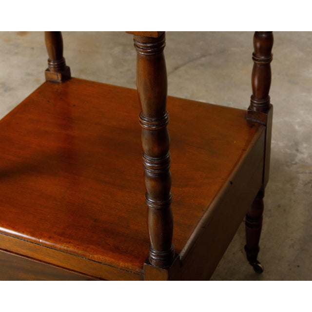 An English mahogany three-tiered étagère from the 19th century with lower drawer, turned supports and casters. This...