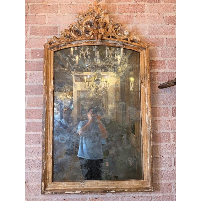 An exceptional Italian Baroque mirror featuring a richly carved giltwood frame with an elegant arched silhouette and an...