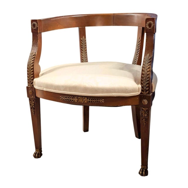An elegant early 20th-century Sheraton-style barrel-back armchair, richly detailed with applied brass ormolu accents and...