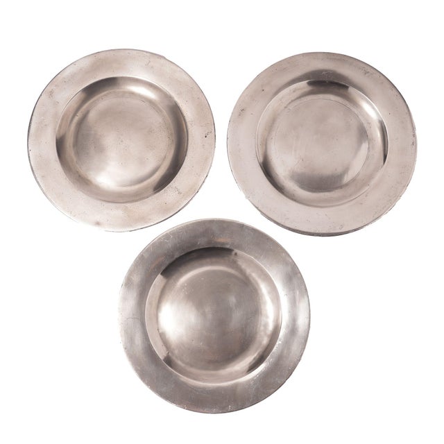 Set of three flat rim pewter plates. One plate is stamped "MDM" on the underside, one plate is stamped "JDM" on the...