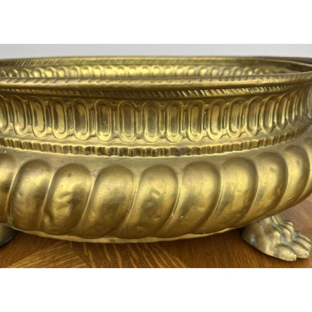 An impressive Vintage brass plant pot featuring striking lion head handles with twisted ring detailing and decorative claw...