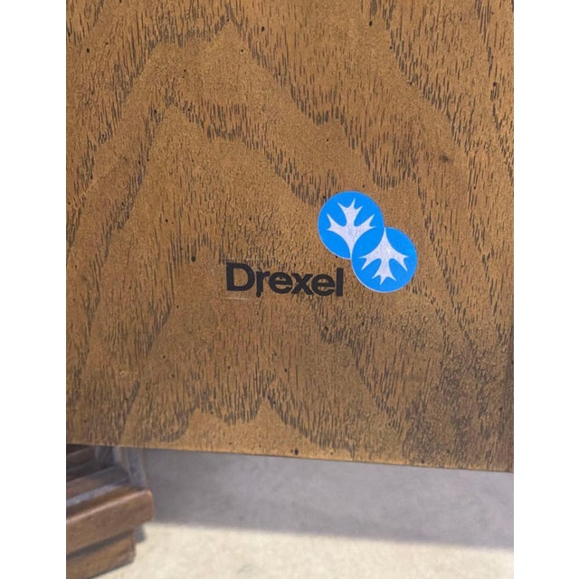 Pair of Drexel walnut end tables with matched starburst veneer tops, shaped corners, and paneled sides. Each has a single...