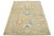 This hand-knotted wool rug features a light brown background with multicolored all-over designs. This rug measures 6'1'' x...