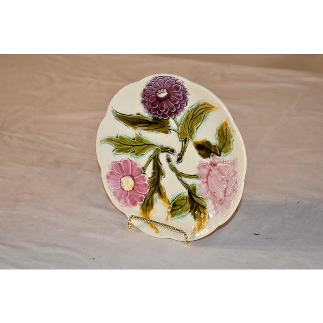 19th century majolica plate from France with a pattern of three flowers. The background of the plate is ivory in color...