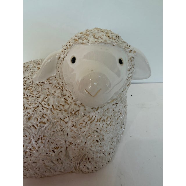 A charming English Staffordshire-style reproduction sculpture depicting a recumbent lamb. The lamb has a sweet, expressive...