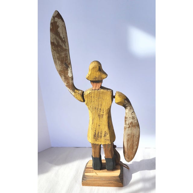 This folk art paddle-armed whirligig sailor in his yellow slicker is the carving of a creative but untrained primitive...