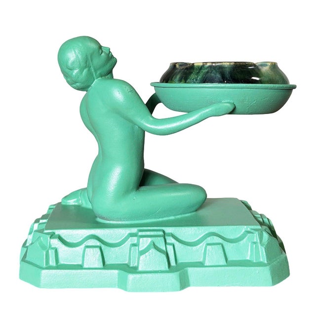 1920s Art Deco ashtray or ring holder by Nuart featuring a nude female figurine offering an ashtray in an oriental red...