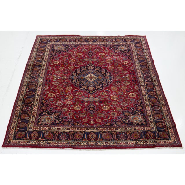 Beautiful vintage Persian Tabriz hand-knotted wool rug with a red field. This piece has a navy blue frame and multicolor...