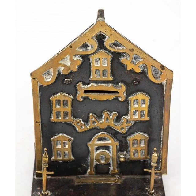 Save your pennies in this charming antique coin bank in the shape of a house. Made from brass with gilded architectural...
