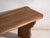 This antique organ bench in solid oak has a plank seat with a raised back lip and rests on two shaped legs cut in a curve....