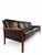 A long, low Hans Olsen rosewood and black leather sofa. The exposed wooden frame creates a warm outline around four loose...