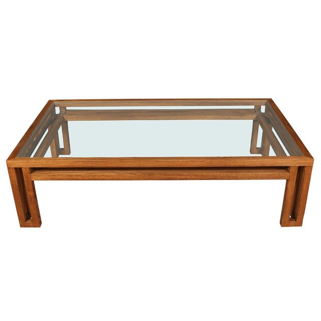 A Billy Baldwin style glass top coffee table with oak base in an open grid design. This modern cocktail table showcases a...