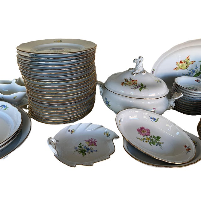 White porcelain dinnerware set, painted in polychrome flowers and highlighted in gold, signed Meissen. The set consists...