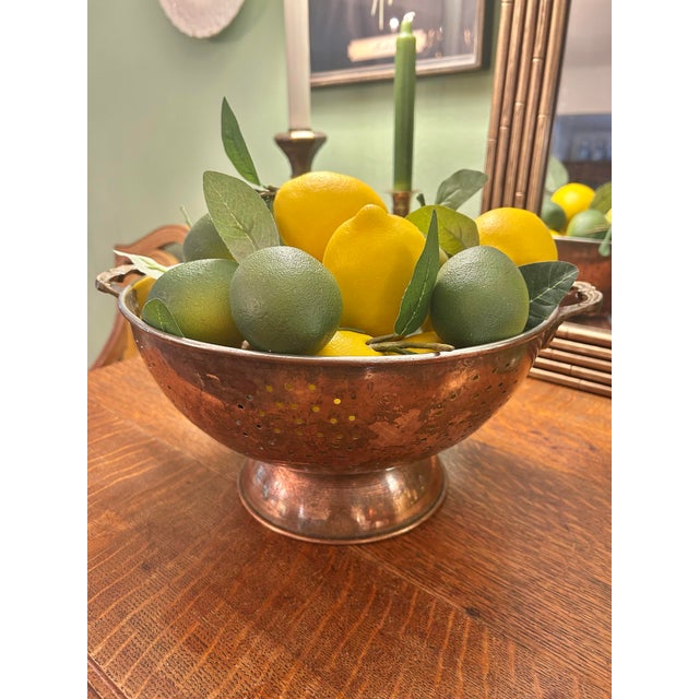 A beautifully aged vintage copper colander elevated on a pedestal foot and fitted with sculptural brass handles, offering...