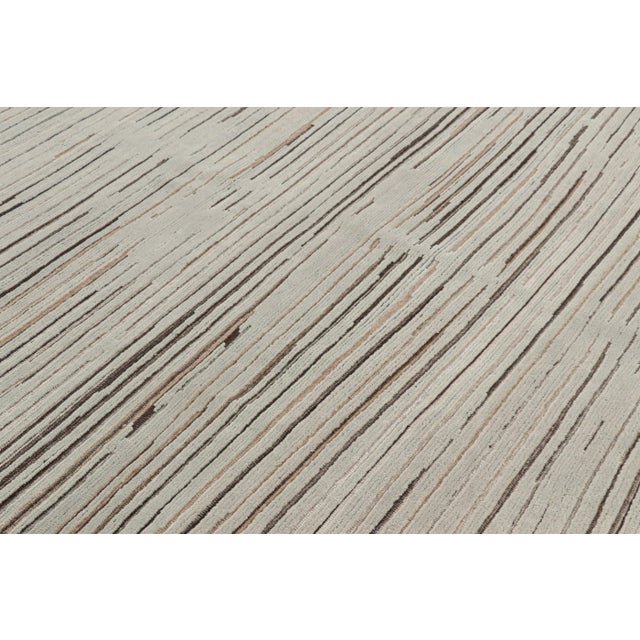 Hand-knotted in wool, this 8x10 textural rug by Rug & Kilim enjoying beige-brown and blue high low stripes, is from our...