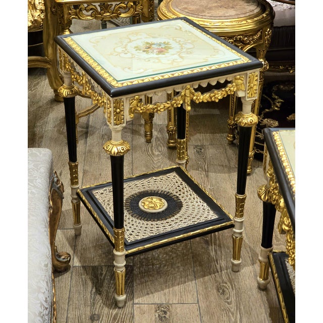 A beautifully detailed French Louis XVI-inspired side table featuring a striking black and white finish accented with...