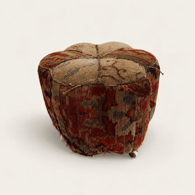 A little footstool covered in a piece of a genuine hand-knotted Oriental carpet, the pile worn down over a century of use...