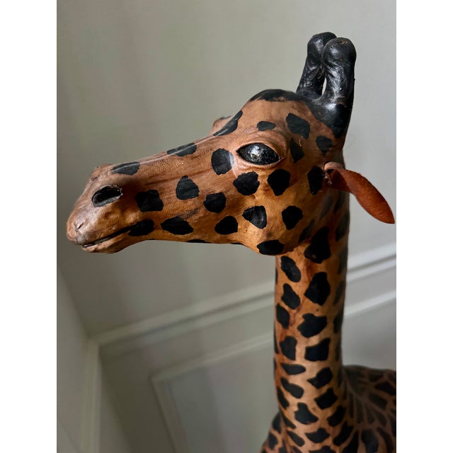 Oversized handcrafted giraffe sculpture wrapped in hand-applied leather with painted detailing. This striking piece stands...