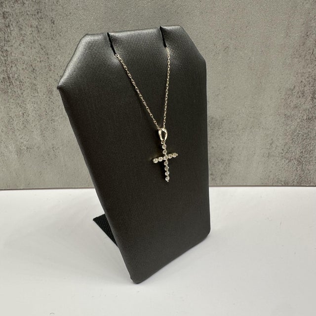 This elegant diamond cross pendant necklace in 10kt yellow gold features 0.25 carats total weight of natural IJ SI round...