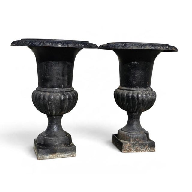 A substantial antique cast iron garden urn planter set of two, featuring an elegant neoclassical form with beautifully...