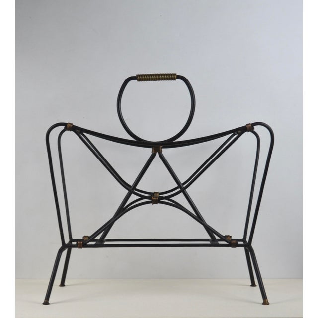 An elegant French modernist magazine rack attributed to Jacques Adnet, dating from the 1950s. Executed in black lacquered...