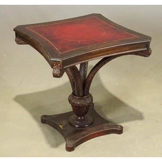 A pair of fancy carved mahogany leather top lamp tables. Inset red burgundy leather tops with gold trim. Styled after the...