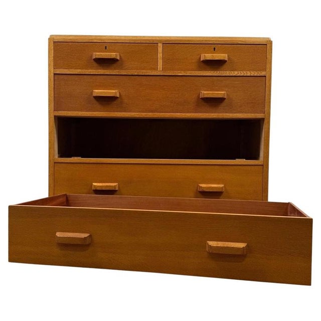 A handsome vintage 20th-century English chest of drawers, finely crafted from golden oak and distinguished by its...